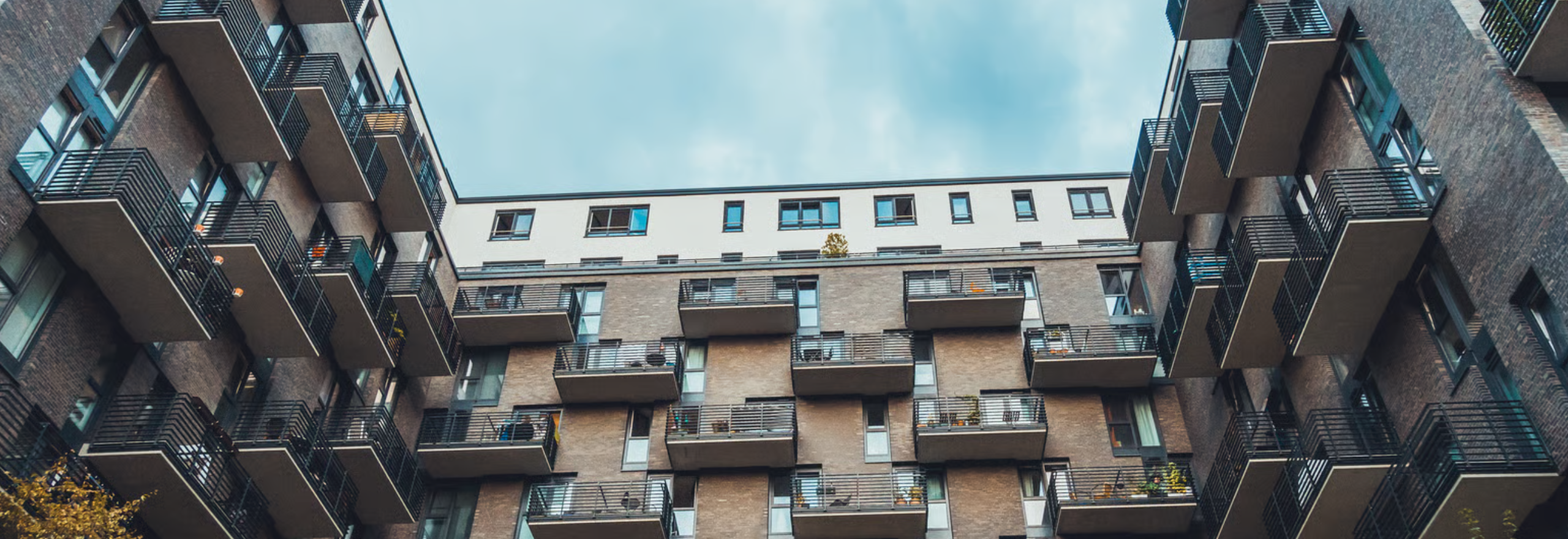 Modern multifamily apartment building with integrated wireless sensors for water leak detection, HVAC monitoring, and BACnet-connected building management system